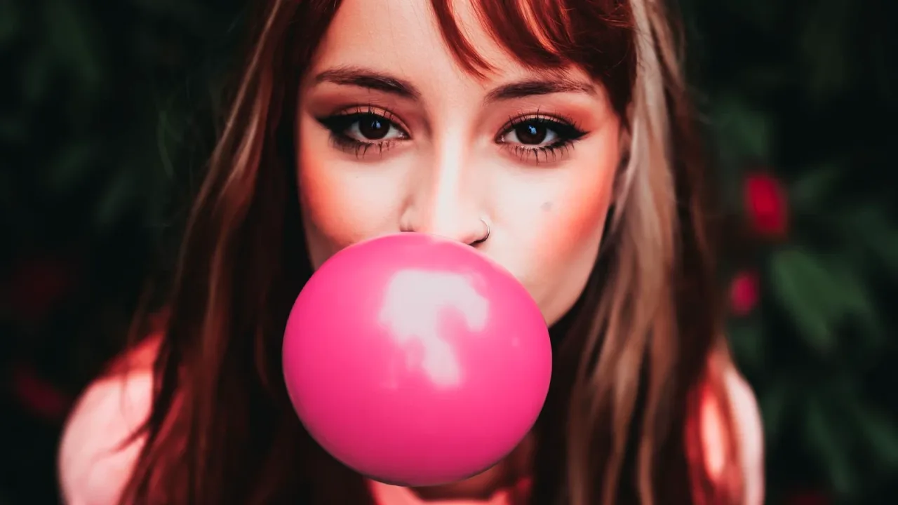 Pembe balon sakızı şişiren genç kadın